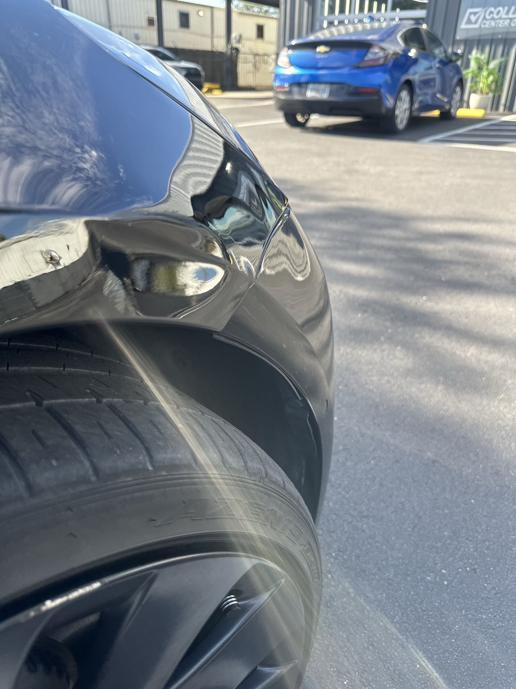 Panel damage on a black Tesla at intake before collision repair at Collision Center Orlando